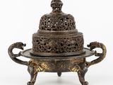 une boîte à encens en bronze richement décorée, munie d'un couvercle et posée sur un socle