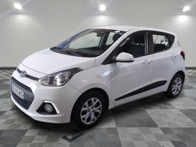 the small white car is parked in a room with a checkered floor