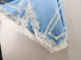 a blue blanket with white lace on it hanging on a wall