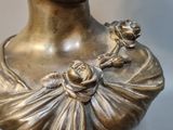 bronze bust of a young girl with a flower in her hair