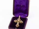 an image of a gold cross pendant in a purple velvet box