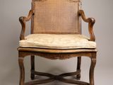 an old chair with a cane back and a cushion on top of it