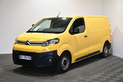 La camionnette jaune est garée dans une pièce blanche au sol à carreaux.