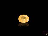 a yellow sapphire stone on a black surface