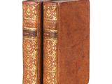 two old books sitting on top of each other on a white surface