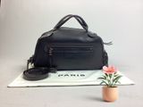 un sac à main noir posé sur une table, à côté d'une fleur