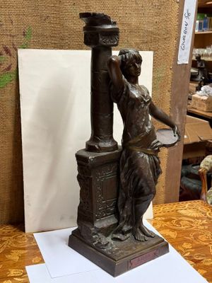 a bronze statue of a woman holding a lamp post