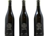 three bottles of wine sitting next to each other on a white surface