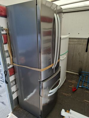 a large silver refrigerator in a room with a ladder