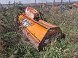 une charrue orange posée au milieu d'un champ, près d'une clôture