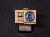 Gros plan sur une bague en or ornée d'un saphir bleu et de diamants