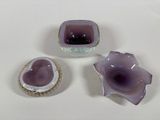 three pieces of purple glass sitting on top of a white table