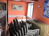 rows of chairs in a room with orange walls and a painting on the wall