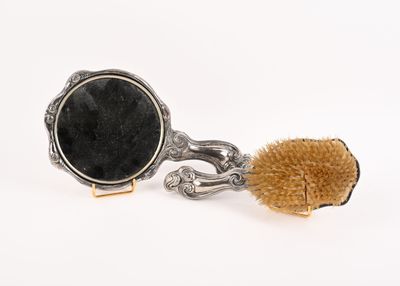 une brosse et un miroir posés sur une surface blanche