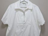 the white shirt is hanging on a hanger on the wall