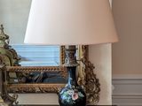 une table noire sur laquelle se trouve une lampe, avec un miroir en arrière-plan