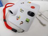 a white camera with stickers on it sitting on a table
