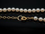 a close up of a white pearl necklace on a black surface