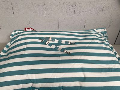 un coussin rayé bleu et blanc posé par terre