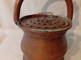 un petit pot marron muni d'une anse, sur fond blanc