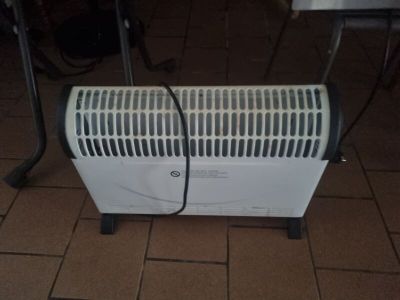 a white heater sitting on a tiled floor next to a table