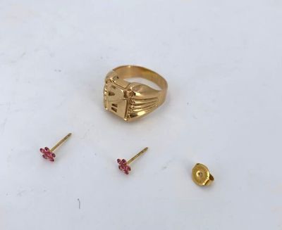 a gold ring with a cross on it next to a pair of studs