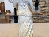 a statue of a woman holding a lamp on a table
