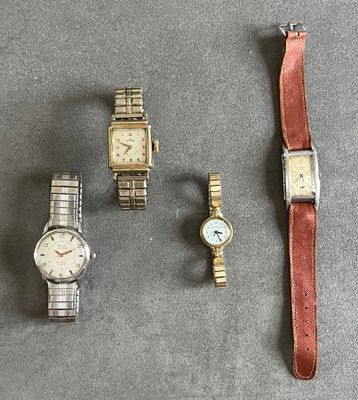 trois montres et un bracelet de montre sont posés les uns à côté des autres