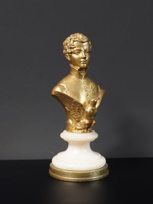 un buste d'homme doré et blanc posé sur un socle en marbre