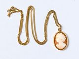 un gros plan d'un collier en or sur lequel figure le portrait d'une femme