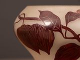 a white vase with a design of leaves on it