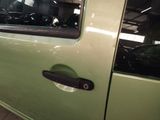 a green car with a black door handle in a garage