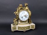 a gold clock with angels on it on a black background
