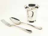 deux cuillères et une fourchette à côté d'une tasse en argent
