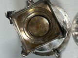 a silver tea pot and a silver plate on a table