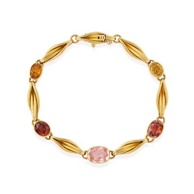 a gold bracelet with multi colored stones on a white background