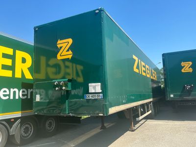 two green semi trucks parked next to each other in a parking lot