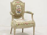 une chaise blanche dont le dossier et les accoudoirs sont recouverts d'un tissu à motifs floraux