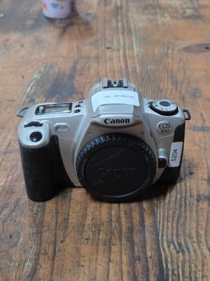 a canon camera sitting on a table with a cup of coffee