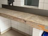 un comptoir en bois dans des toilettes publiques, avec une poubelle bleue