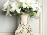 a white vase with white flowers in it on a table