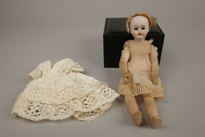 an image of a doll is sitting next to a dress on a table