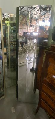 un homme debout devant un grand miroir dans une pièce