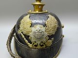 an old helmet with a gold eagle on it sitting on a white surface