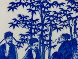 blue and white plate with a painting of a group of people in a garden