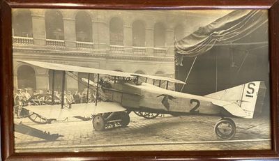 photo encadrée représentant un vieil avion à l'intérieur d'un bâtiment, avec une foule de personnes