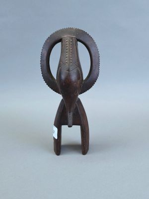 une image représentant une petite statue d'éléphant en bois posée sur une surface grise