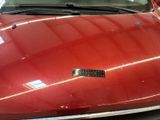 a red car parked in a garage with a sticker on the hood