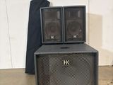 two black speakers sitting on top of each other in front of a white wall