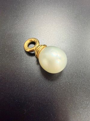 un pendentif plaqué or orné d'une perle blanche sur un fond noir